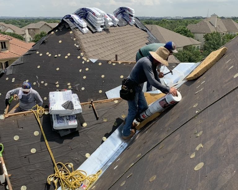 Construction workers installing a new shingle roof in Central Texas.