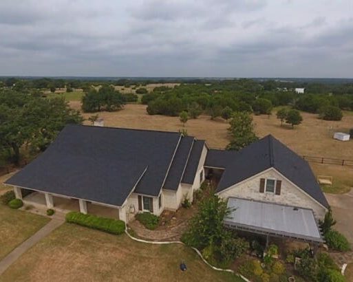 Austin roof that is dark grey. The house is made of limestone.