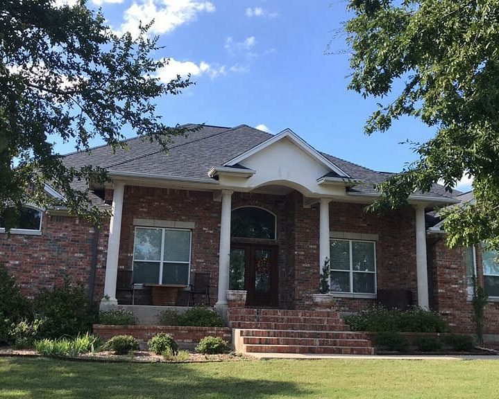 Red brick home with shingle roof installed by A&W Roofing Austin.