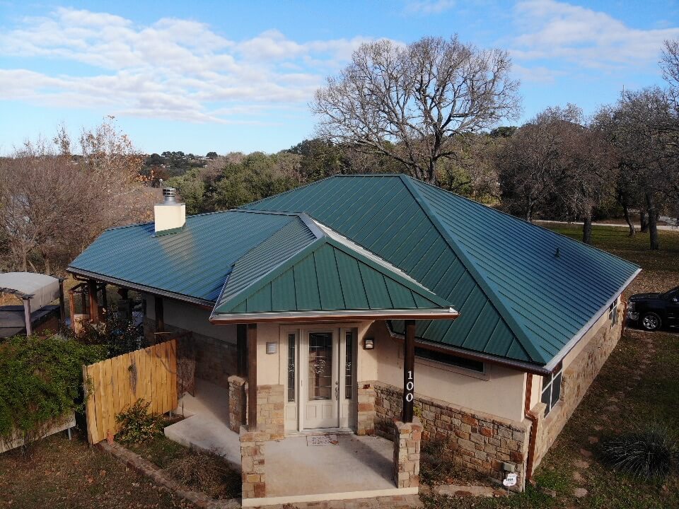 Green metal roof on Burnet, Texas home with large outdoor space and small front porch.