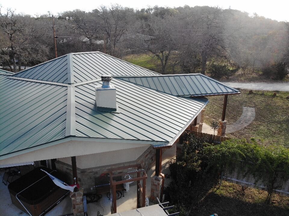 Outdoor patio in Burnet with jacuzzi, an outdoor shower, and a green metal roof.