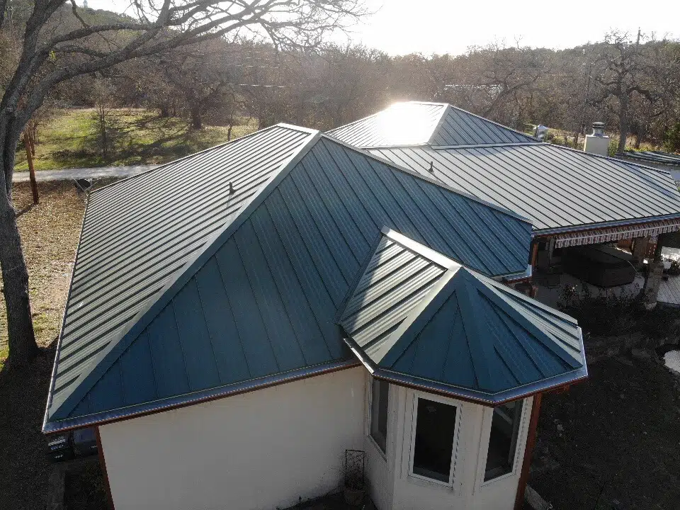 Patio in Burnet, Texas with outdoor shades, plants, and a green metal roof.