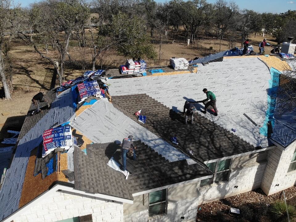 Four roofing contractors installing new shingles on a home in Liberty Hill.