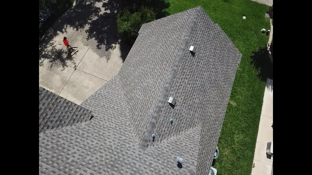 Shingle roof in Pflugerville and a man leaf blowing the driveway.