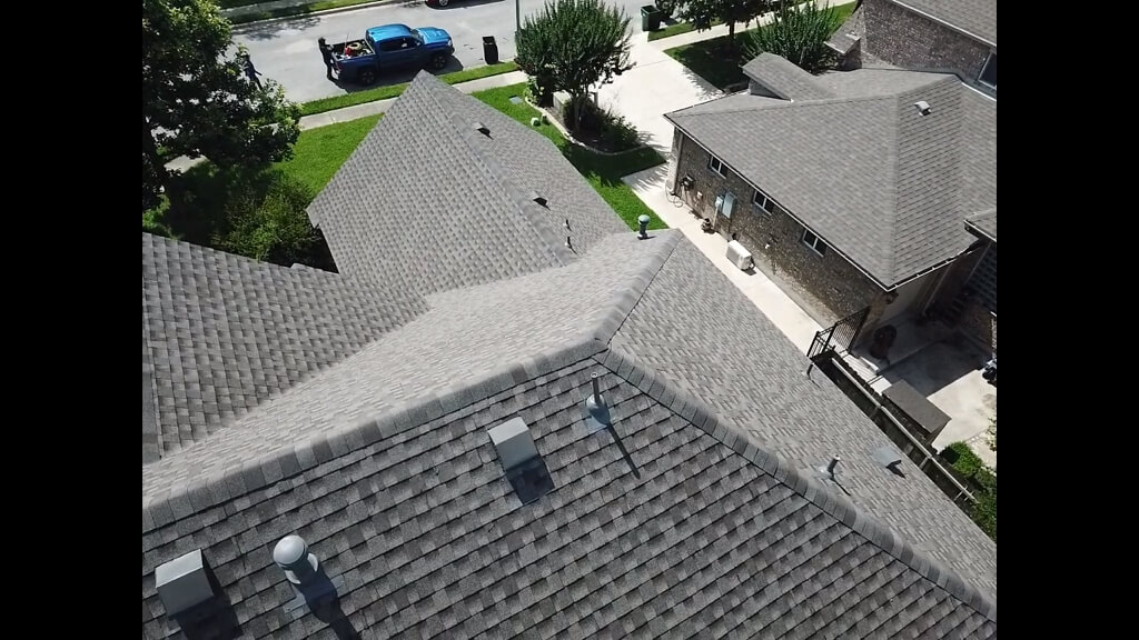 Shingle roof in Round Rock with a blue truck parked in the street.