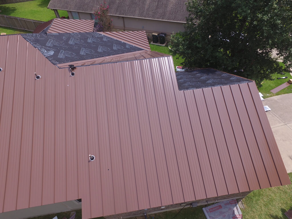 A&W roofing contractors in the process of installing a red metal roof on a home in Georgetown.
