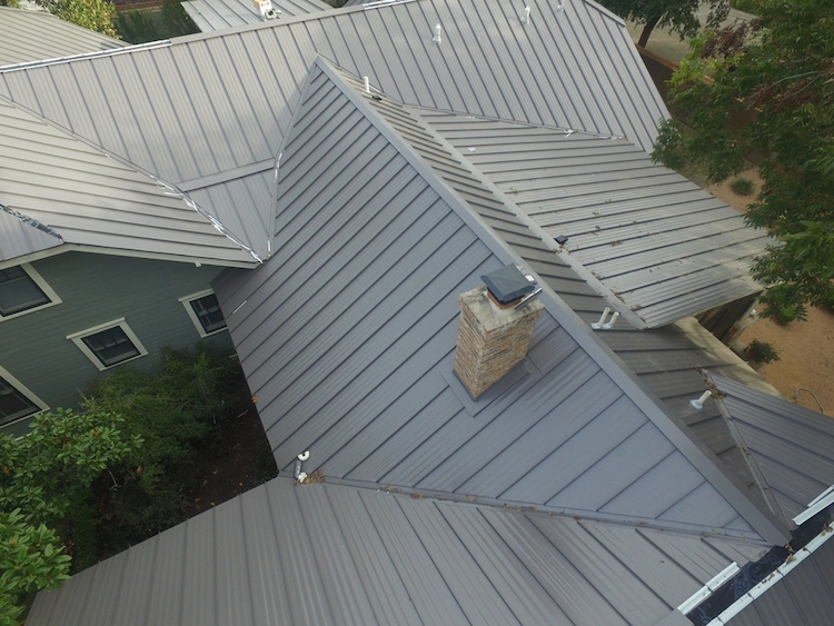 Dark gray colored metal roof in Austin. They home has a green wooden exterior.