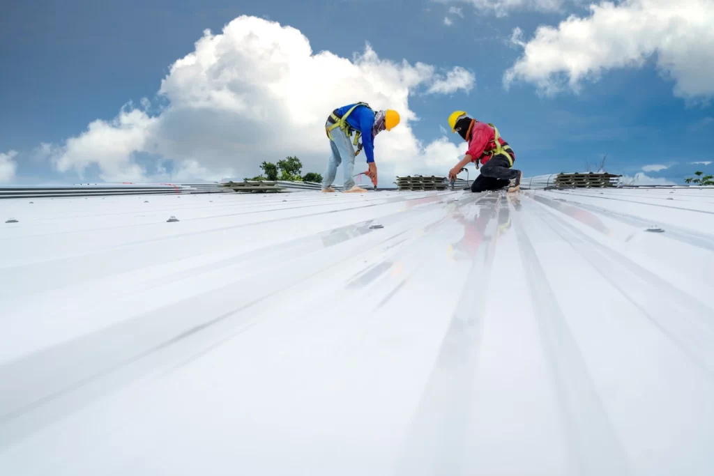 Two roofing contractors in Austin installing a metal commercial roof.