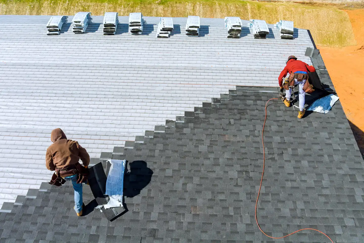 Two roofing contractors in Austin adding GAF shingles to a roof.