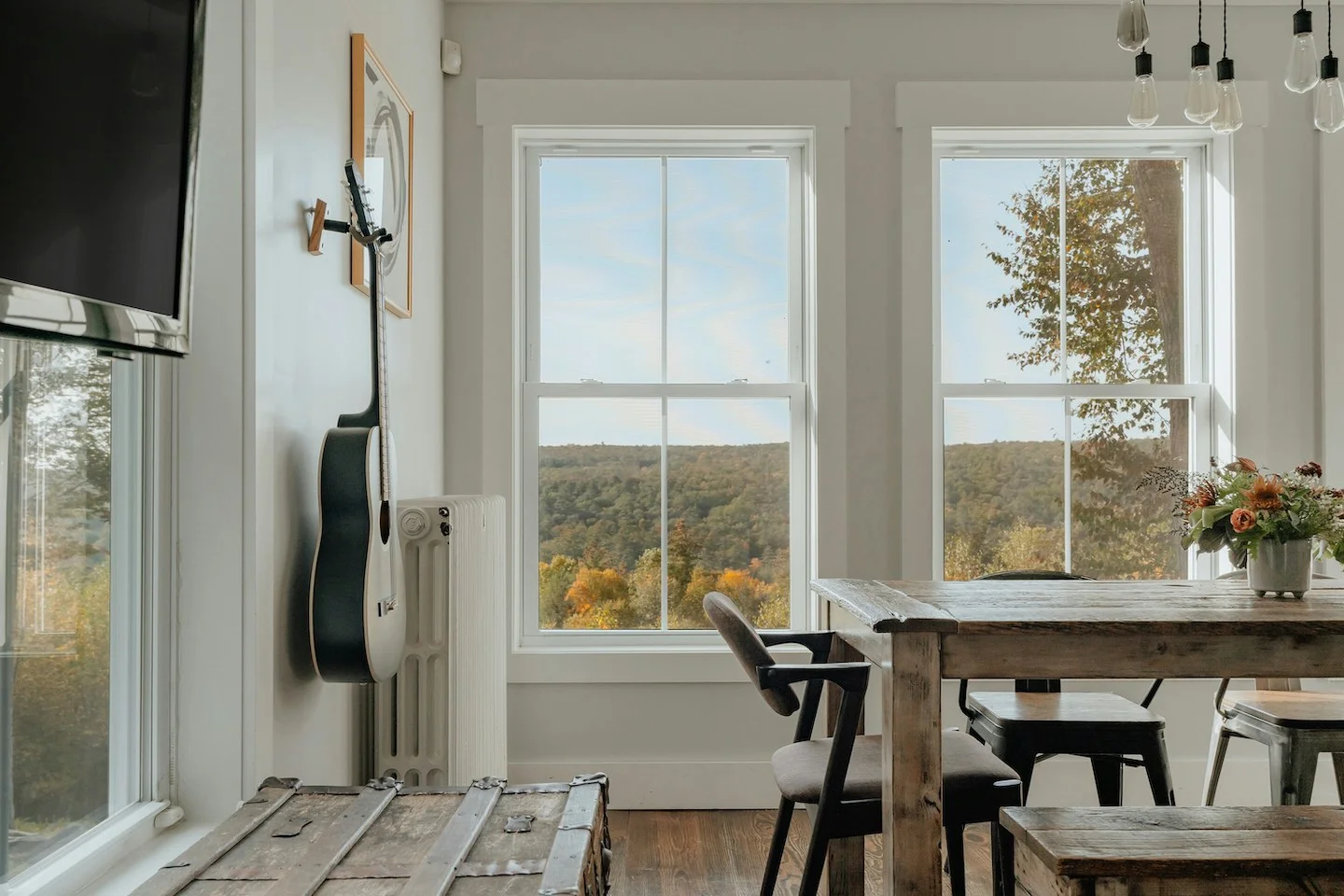 Dining room in Austin, Texas with guitar hanging on wall and wooden dining table.
