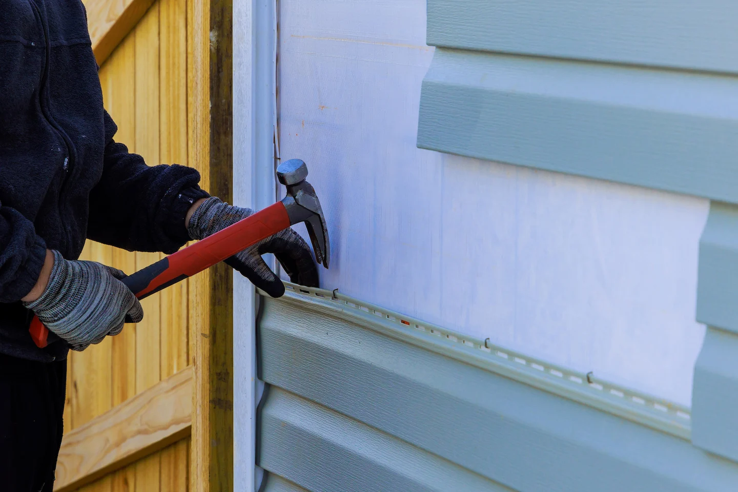 Technician using pliers to remove existing siding panels.